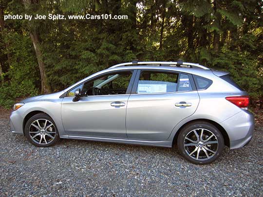 side view 2017 Subaru Impreza Limited 5 door hatchback has 17" machined alloys, silver fog light trim, silver roof rack rails, silver door handles. Ice silver color shown.  Optional aero cross bars